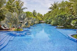 una piscina con acqua blu e palme di Da Nang Beach Villa Resort a Da Nang