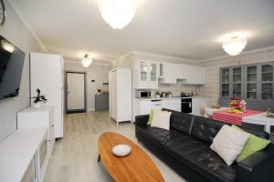 ein Wohnzimmer mit einer schwarzen Couch und einer Küche in der Unterkunft Жк Арбат двух комнатная in Almaty