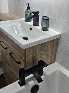 a white bathroom sink with a black faucet at Glebe Apartment in Campbeltown +28 photos