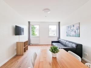 - un salon avec un canapé noir et une table en bois dans l'établissement RAJ Living - 4 Zimmer Wohnung - 25 Min zur Messe DUS, à Krefeld