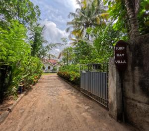 a dirt road leading to a house with a gate and a sign at SurfBayVilla in Dickwella