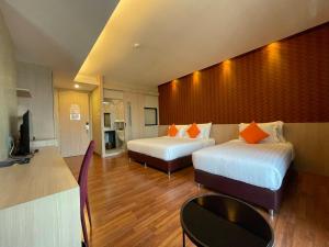 a hotel room with two beds and a television at Tonaoi Grand Hotel in Hat Yai