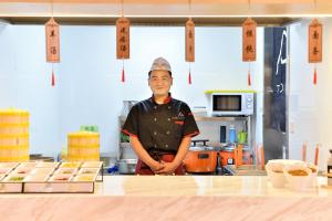 Um homem está de pé numa cozinha. em Atour Light Hotel Shenyang Tiexi Plaza Wanxianghui em Shenyang