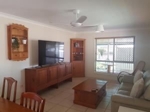Banya Bliss - Guest House في Bongaree: غرفة معيشة مع تلفزيون وأريكة وطاولة