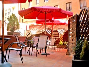 a table and chairs under a red umbrella on a patio at Hotel Murrieta in Logroño