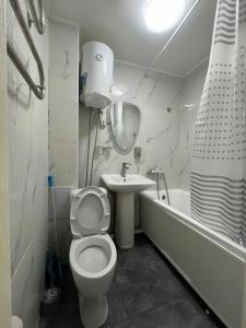 a white bathroom with a toilet and a sink at 1-комн квартира в центре города in Qyzylorda