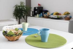 una mesa con un plato verde y dos tazas en ella en Comeacasatua en Bari