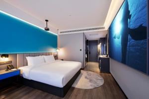 una camera d'albergo con letto e parete blu di Mehood Hotel Hanzhong Central Plaza ad Hanzhong