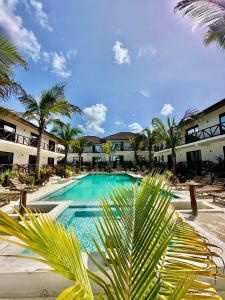 a swimming pool with palm trees in front of a resort at Sand Beach Boutique Hotel in Bwejuu