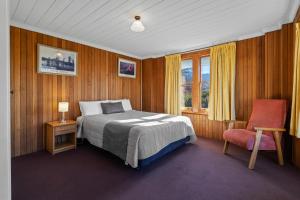 a bedroom with a bed and a chair and a window at Riverfront Motel & Restaurant in Hobart