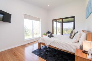 um quarto branco com uma cama e janelas grandes em Beefsteak Homestead em Kingston