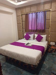 um quarto com uma cama grande e almofadas roxas em Hotel Karnavati em Ahmedabad