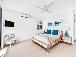 a white bedroom with a bed and a chair at White Sails 4 - Amazing views over Convent in Yamba