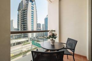 d'une table avec des chaises et un vase de fleurs sur le balcon. dans l'établissement Sunkissed holiday homes 2-3BR Apartments on JBR beach near mall & metro & bluewaters Island, à Dubaï