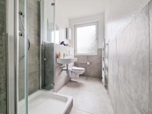 La salle de bains est pourvue de toilettes, d'un lavabo et d'une douche. dans l'établissement RAJ Living - 4 Zimmer Wohnung - 25 Min zur Messe DUS, à Krefeld