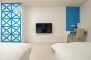 um quarto com duas camas e uma televisão na parede em LJ Hotel em Kaohsiung