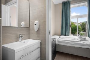 a bathroom with a sink and a bed with a window at Stay Byparken - Self-Service Hotel in Bergen +150 photos
