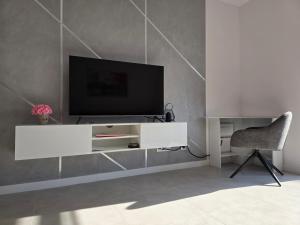 un salon avec une télévision et une chaise dans l'établissement Kolo Apartament, à Koło