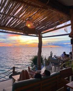 - un groupe de personnes assises sur une terrasse pour admirer le coucher du soleil dans l'établissement Siam Cookies Cottage, à Haad Pleayleam