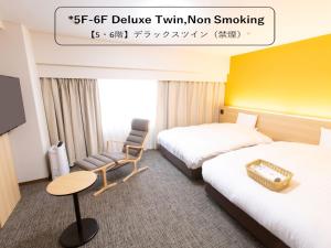 a hotel room with two beds and a chair at Toyama Chitetsu Hotel in Toyama