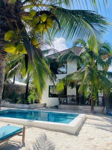 a villa with a swimming pool and a palm tree at Sand Beach Boutique Apartments in Bwejuu