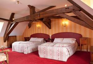 two beds in a room with wooden ceilings at Château de Rigny in Gray