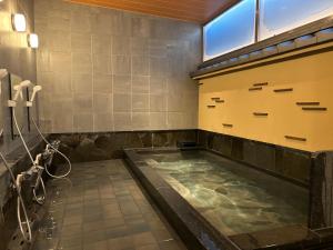 a large tub in a bathroom with a shower at Matsumoto Ryokan in Kyoto