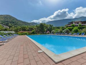 una piscina con sedie e montagne sullo sfondo di NISPORTO APPARTAMENTO 100 MT DAL MARE E PISCINA a Nisporto