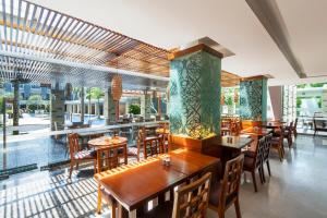 een restaurant met houten tafels, stoelen en ramen bij Swiss-Belhotel Danum Palangkaraya in Palangkaraya