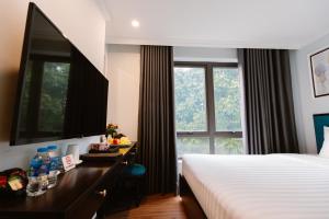 a hotel room with a bed and a desk and a window at Hồng Vận Hotel in Hanoi