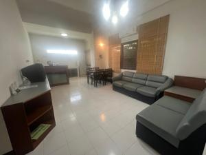 a living room with a couch and a tv and a table at Muang Thong Family Suite Hatyai in Hat Yai
