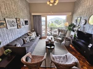 een woonkamer met een bank, stoelen en een televisie bij Green Hill Tanah Rata Cameron Highland in Tanah Rata