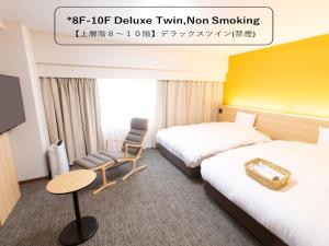una habitación de hotel con 2 camas y una silla en Toyama Chitetsu Hotel en Toyama