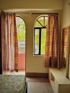 a room with a bed and a window with curtains at JWALA JAIPUR in Jaipur