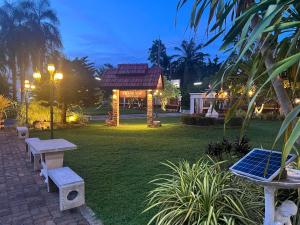 Muang Thong Family Suite Hatyai في هات ياي: حديقة بها كراسي وشرفة في الليل
