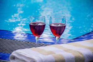 two glasses of wine sitting next to a swimming pool at Loony Villa in Negombo