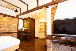 1 dormitorio con TV de pantalla plana grande en una pared de ladrillo en LCO-Resort, en Takizawa