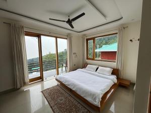 ein Schlafzimmer mit einem Bett und einem großen Fenster in der Unterkunft Hide Out Stays in Dharamshala
