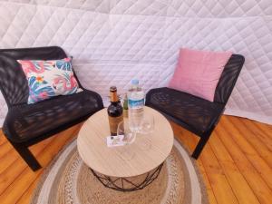 un soggiorno con 2 sedie e un tavolo con 2 bottiglie di Domes1 Tenerife, lujo con el encanto de acampar a Arico