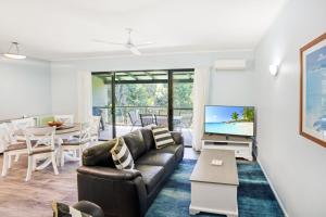 a living room with a couch and a tv at Baden 58 - Rainbow Shores. Aircon. Wifi. Pools Walk to beach in Rainbow Beach