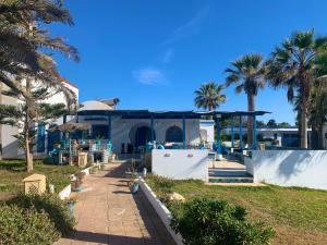 a building with palm trees and a sidewalk at Villa Acqua en front de mer in Nabeul +36 photos