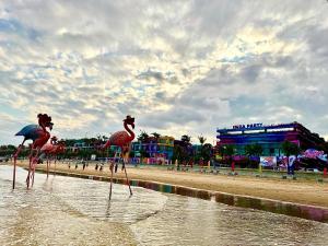 two flamingos standing in the water on a beach at The Lucky House in Thanh Hóa