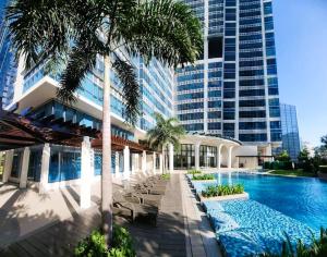 um grande edifício com piscina e palmeiras em 4 Pax Cozy Uptown Mall Unit with Balcony and Parking em Manila