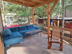 a blue couch on a porch with a table and a chair at Leśne Zacisze in Wijewo