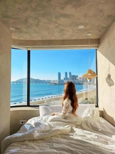 a girl sitting on a bed looking out at the ocean at Paradise on earth in Busan