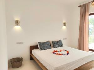a bedroom with a bed with a flower necklace on it at Luxury White Villa in Nungwi