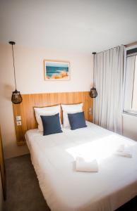 1 dormitorio con 1 cama blanca grande con almohadas azules en Les Maritimes en Seignosse