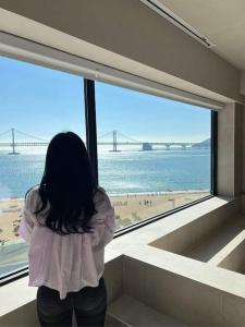 a woman looking out of a large window at a beach at Paradise on earth in Busan