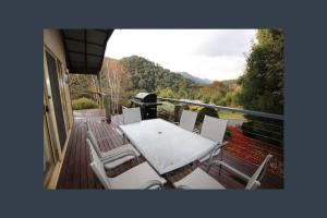 Un patio con una mesa y sillas en una terraza. en Buller House Merrijig, en Merrijig