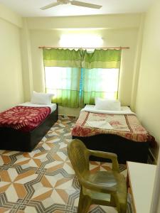 a room with two beds and a chair in it at Mangal homestay in Pokhara